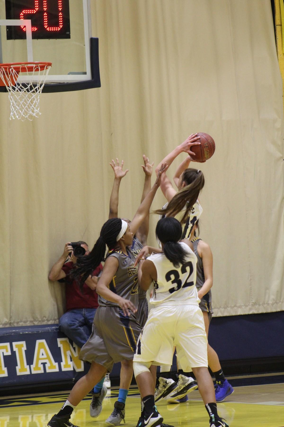 Basketball player in mid shot, as she's being guarded by the other team.